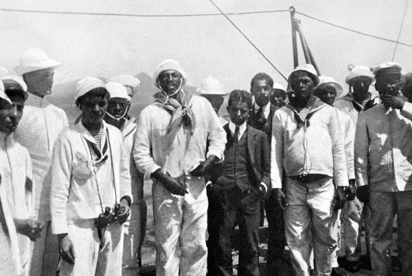João Cândido Felisberto, centre at left of man in suit, stands among other sailors on the deck of a Brazilian warship in 1910.