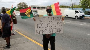 A protester holds a sign during a rally to demand that the United Kingdom make reparations for slavery, ahead of a visit to Jamaica by the Duke and Duchess of Cambridge as part of their tour of the Caribbean, outside the British High Commission, in Kingston, Jamaica March 22, 2022.