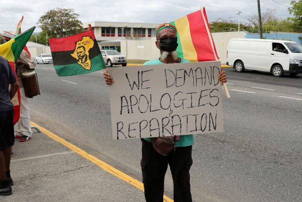 A protester holds a sign during a rally to demand that the United Kingdom make reparations for slavery, ahead of a visit to Jamaica by the Duke and Duchess of Cambridge as part of their tour of the Caribbean, outside the British High Commission, in Kingston, Jamaica March 22, 2022.