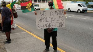 A protester holds a sign during a rally to demand that the United Kingdom make reparations for slavery, ahead of a visit to Jamaica by the Duke and Duchess of Cambridge as part of their tour of the Caribbean, outside the British High Commission, in Kingston, Jamaica March 22, 2022.