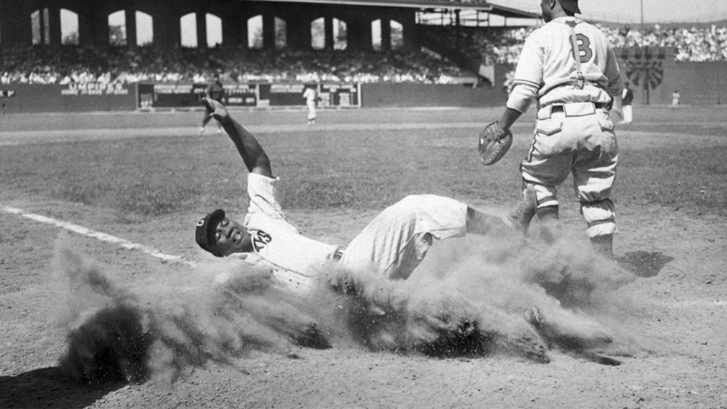 Negro Leagues superstar Josh Gibson creates a cloud of dust as he slides into home plate during the fourth inning of a 1944 game in Chicago.