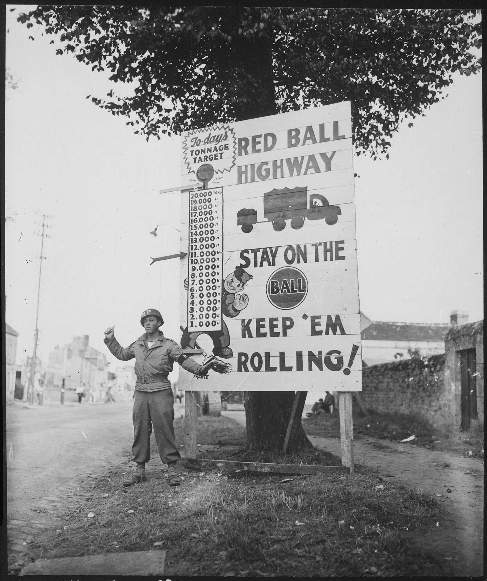 In this Sept. 5, 1944, photograph, Cpl. Charles H. Johnson of the 783rd Military Police Battalion waves on a Red Ball Express convoy near Alenon, France. National Archives