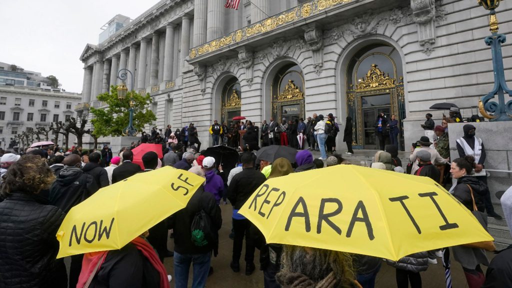 A crowd listens to speakers at a reparations rally outside City Hall in San Francisco on March 14, 2023.