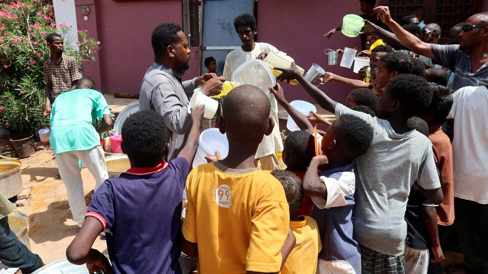 People hold pots as volunteers distribute food in Omdurman, Sudan, September 3, 2023.