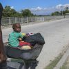 A man pushes a child in a wheelbarrow along a street in Pont-Sonde, Haiti, Monday, Oct. 7, 2024, days after a gang attacked the town.