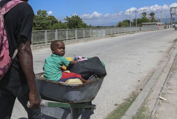 A man pushes a child in a wheelbarrow along a street in Pont-Sonde, Haiti, Monday, Oct. 7, 2024, days after a gang attacked the town.