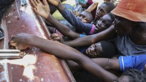 People displaced by armed attacks receive food from a nongovernmental organization in Saint-Marc, Haiti, Sunday, Oct. 6, 2024.