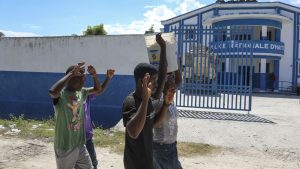 People raise their arms while walking past a police station in Pont-Sonde, Haiti, Monday, Oct. 7, 2024, days after a gang attacked the town.