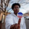 Young Black male holding "voted" sticker