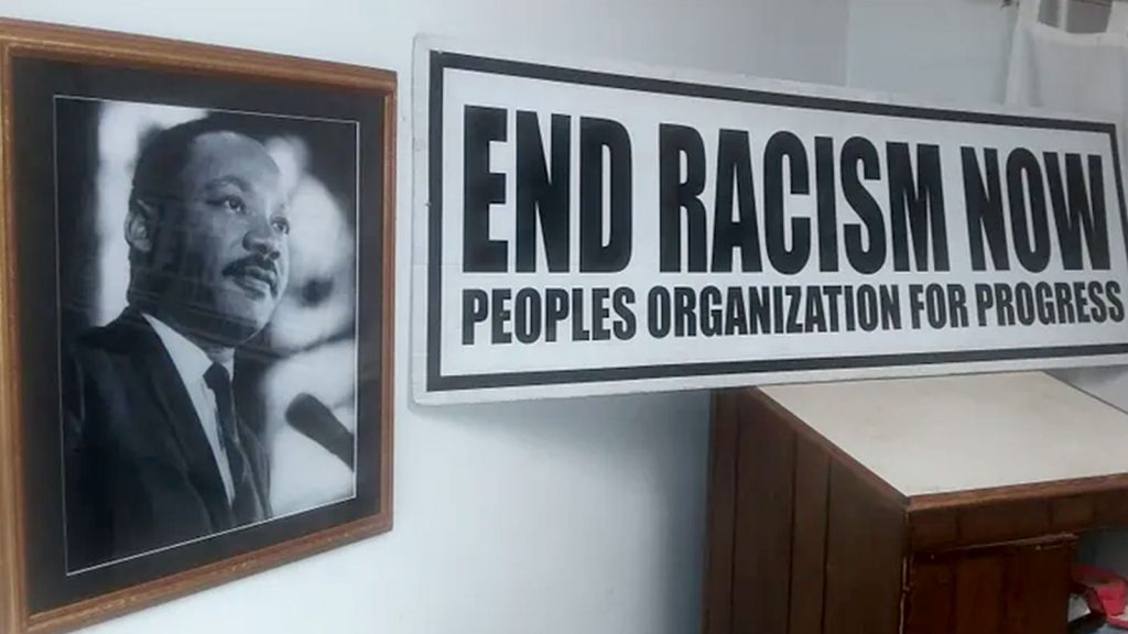 Framed photo of Martin Luther King Jr an an "End Racism Now" sign from Peoples Organization for Progress (POP).