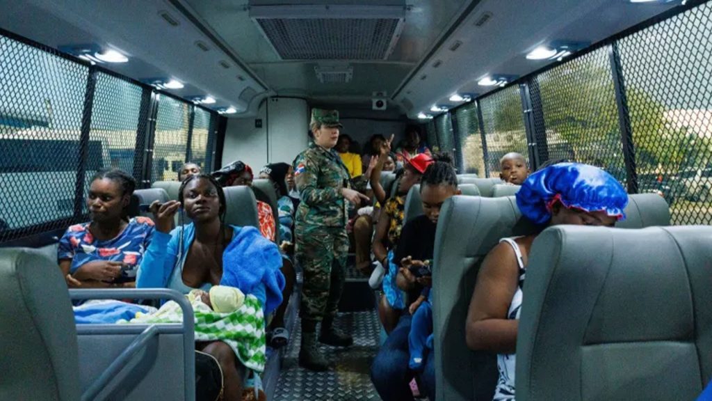 A soldier chats with a Haitian mother on a bus heading to the border of the Dominican Republic and Haiti where she is being deported.