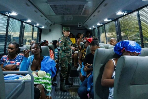 A soldier chats with a Haitian mother on a bus heading to the border of the Dominican Republic and Haiti where she is being deported.