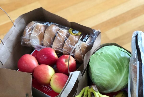 Grocery bags filled with fresh food items on a kitchen floor (Maria Lin Kim, Unsplash)