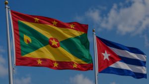 Flags of Grenada and Cuba waving side by side against a blue sky.